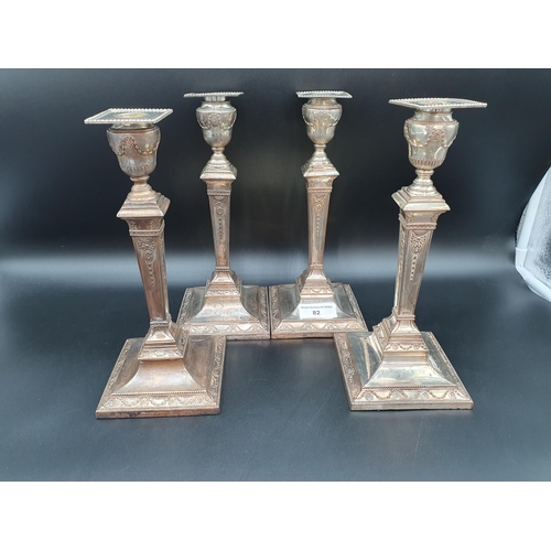 82 - A Set of four Sheffield plated Pillar Candlesticks decorated swags, ribbons and paterae on beaded sq... 