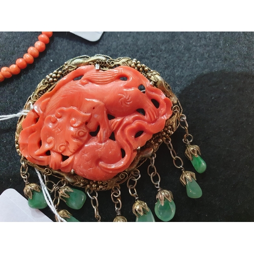 170 - A Coral bead Necklace and a Coral Brooch with carved dragon in gilt metal frame suspending polished ... 