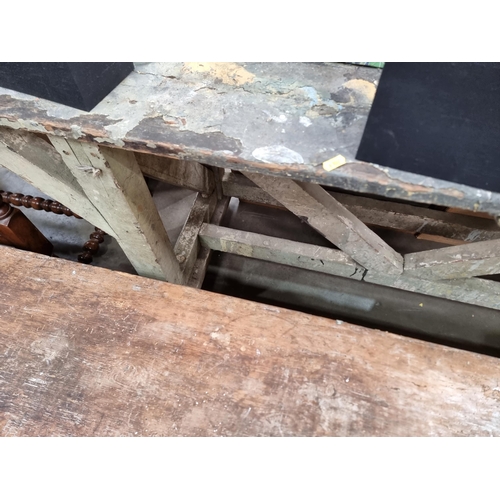 581 - A painted industrial Artists Table/Bench on square supports and stretchers and large metal castors, ... 