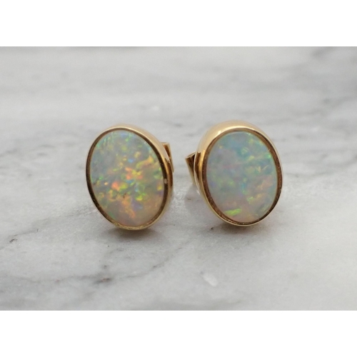 157 - A pair of Opal Ear Studs each rubover-set oval stone in 18ct gold