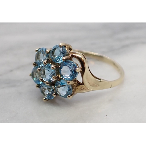 164 - A Blue Topaz Cluster Ring claw-set seven round stones in 9ct gold, ring size M 1/2