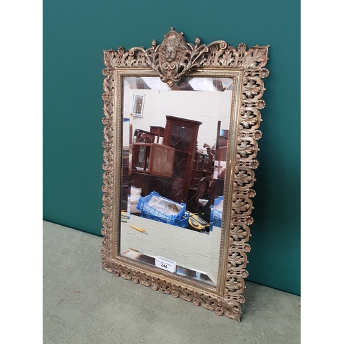 244 - A brass framed Wall Mirror with cherub mask surmount, bevelled plate and pierced border, 16 x 11in, ... 