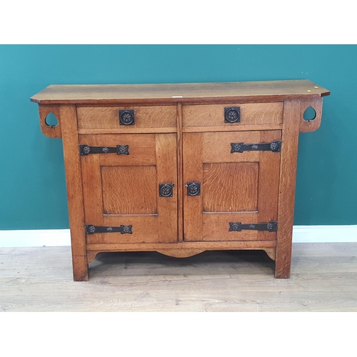 33 - An oak Arts and Crafts Sideboard with pierced spade design fitted two frieze drawers above a pair of... 