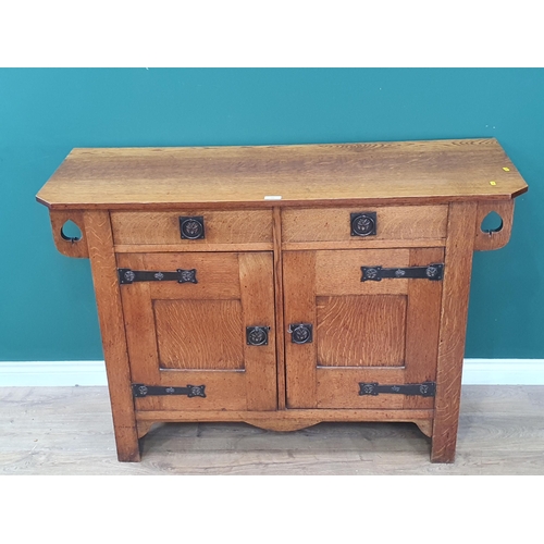 33 - An oak Arts and Crafts Sideboard with pierced spade design fitted two frieze drawers above a pair of... 