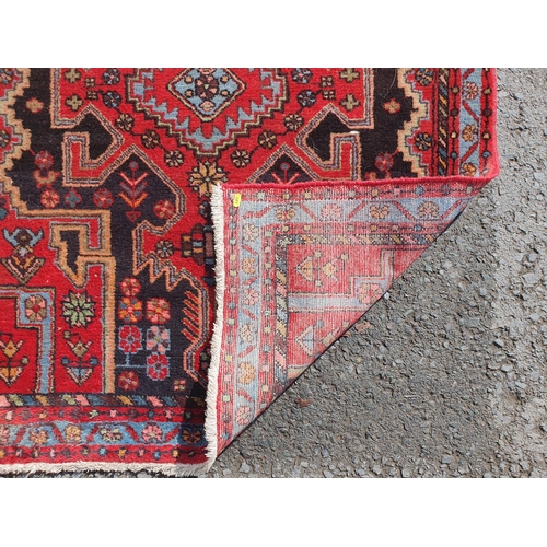 398 - A Persian Style Rug on red ground with central stylised lozenge with floral border, 4ft 11