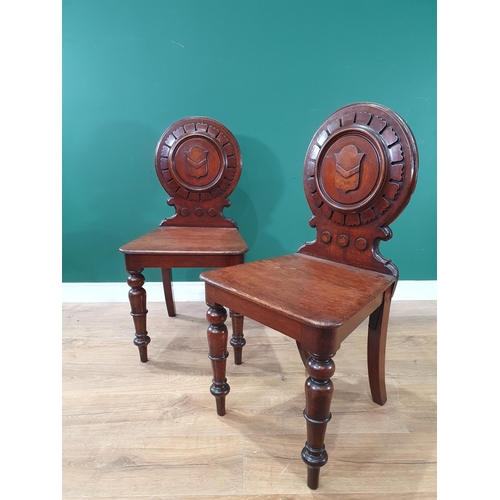 572 - A pair of 19th Century oak Hall Chairs with carved circular backrests with carved shield decoration,... 