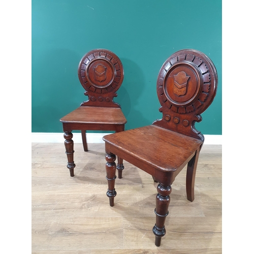 572 - A pair of 19th Century oak Hall Chairs with carved circular backrests with carved shield decoration,... 