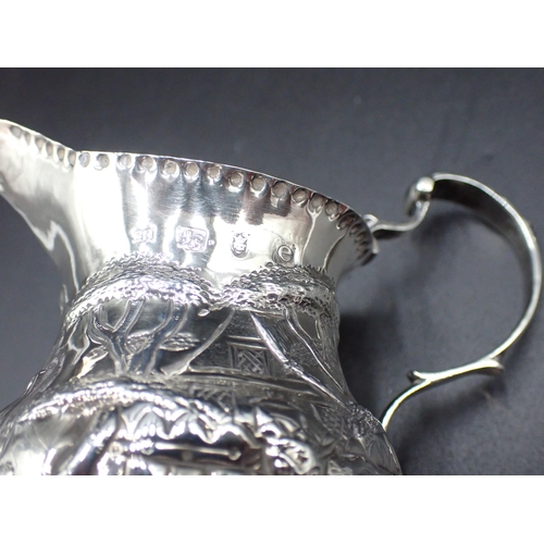 129 - A George III silver helmet shape Jug with later embossing and chasing of landscape with animals and ... 