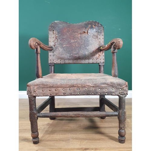 22 - An antique oak framed leather upholstered Armchair, with shaped backrest, scrolled arms on turned su... 