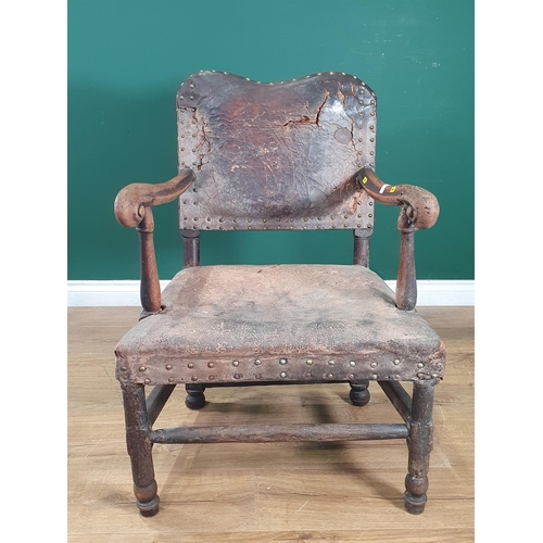 22 - An antique oak framed leather upholstered Armchair, with shaped backrest, scrolled arms on turned su... 