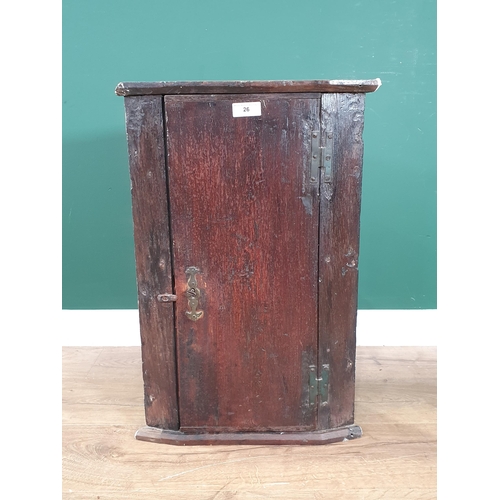 26 - An antique oak Hanging Corner Cupboard the single door enclosing two fitted shelves, 2ft 2