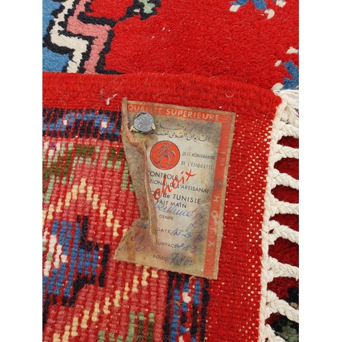 727 - A Tunisie bordered Rug with central red lozenge on a blue ground, 5ft 10in x 3ft 7in