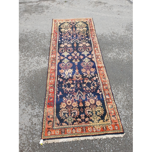 729 - A bordered Persian style Runner with floral designs on a blue ground, 10ft 7in x 3ft 10in