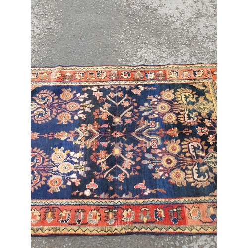 729 - A bordered Persian style Runner with floral designs on a blue ground, 10ft 7in x 3ft 10in