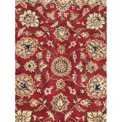 733 - An Indian woollen Carpet, with floral designs on a red ground, 10ft 9in x 7ft 11in