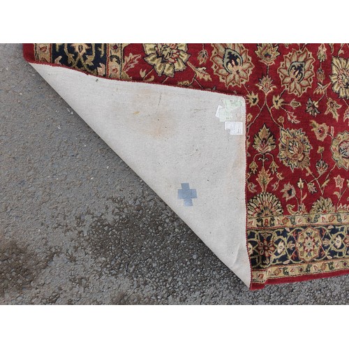 733 - An Indian woollen Carpet, with floral designs on a red ground, 10ft 9in x 7ft 11in