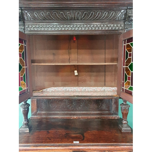 644 - A Victorian carved oak Cupboard with upper section fitted two lead glazed doors above base fitted pa... 