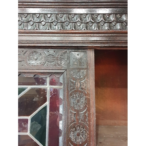 644 - A Victorian carved oak Cupboard with upper section fitted two lead glazed doors above base fitted pa... 