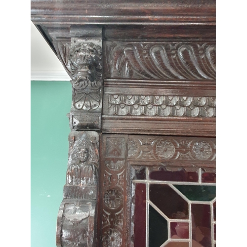 644 - A Victorian carved oak Cupboard with upper section fitted two lead glazed doors above base fitted pa... 