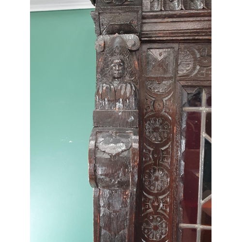 644 - A Victorian carved oak Cupboard with upper section fitted two lead glazed doors above base fitted pa... 