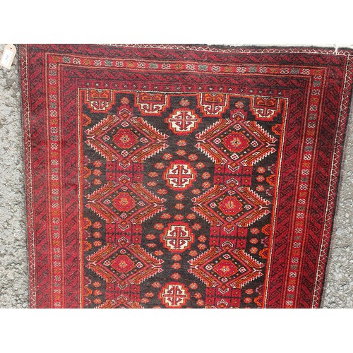 450 - A woollen red ground Rug with two rows of interlocking lozenges 6ft 6in L x 3ft 3in W (R4)