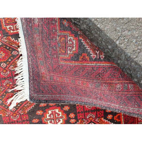 450 - A woollen red ground Rug with two rows of interlocking lozenges 6ft 6in L x 3ft 3in W (R4)