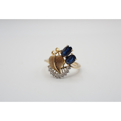197 - A Sapphire and Diamond Ring claw-set two oval-cut sapphires and leaf shaped plaque above arc of eigh... 