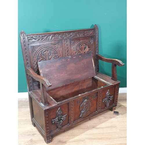 474 - An oak Box Settle with carved panel back, lift up seat, above three panel front with carved applied ... 