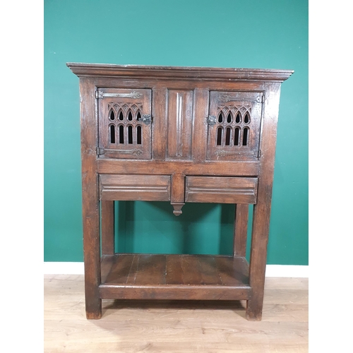 581 - An oak Cupboard in the 16th Century style fitted with pair of pierced Gothic arched doors above two ... 