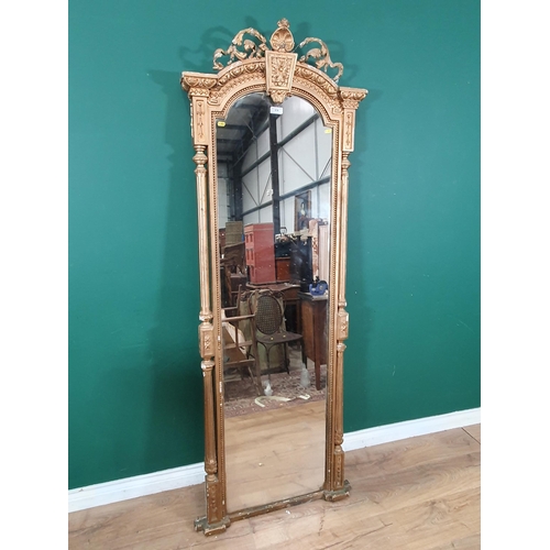 A narrow gilt framed Hall Mirror with arched top carved with floral and