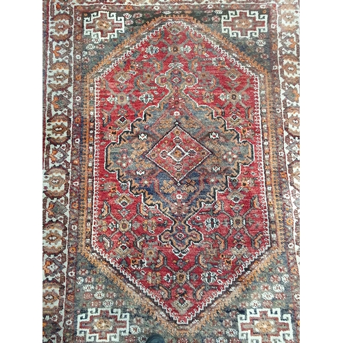 276 - A Persian Rug with multiple borders and large central medallion on a red ground, 6ft 4in x 4ft 6in