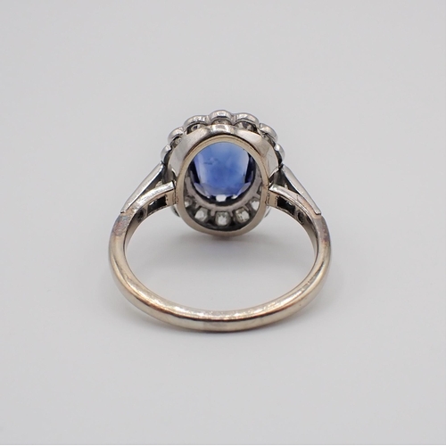 148 - A Sapphire and Diamond Cluster Ring claw-set oval-cut sapphire within a frame of millegrain-set old-... 