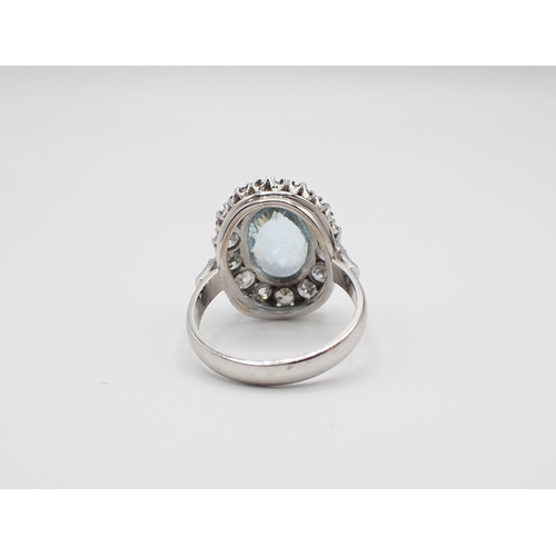 156 - An Aquamarine and Diamond Cluster Ring claw-set oval mixed-cut aquamarine within a frame of pavé-set... 