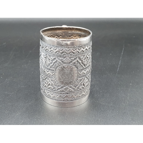 23 - A Victorian silver Mug with all over floral embossing, Birmingham 1889, and a white metal Matchbox H... 