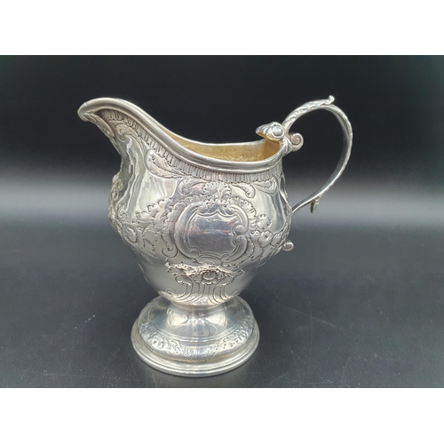 24 - A George III silver Jug with floral swag embossing, leafage scroll handle on pedestal base, London 1... 