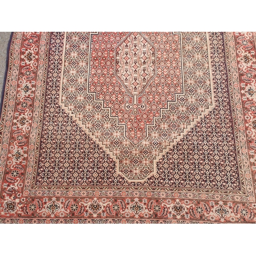 418 - A modern Persian Rug with pink central lozenge on blue ground with pink border with stylised flowers... 