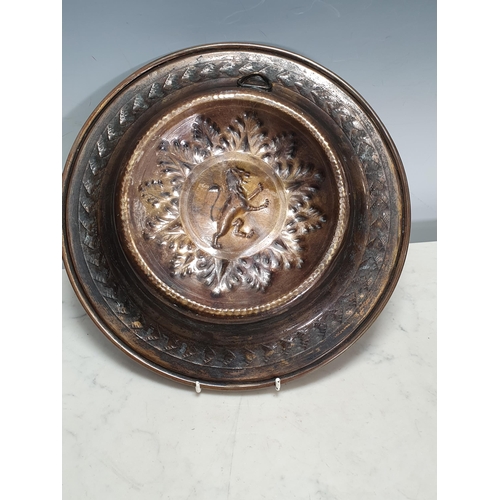 445 - An embossed brass Dish with central rampant lion, 12in diam