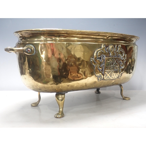 446 - A two handled brass Jardiniere, oval and with embossed coat of arms on four paw supports, 2ft W