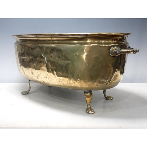 446 - A two handled brass Jardiniere, oval and with embossed coat of arms on four paw supports, 2ft W