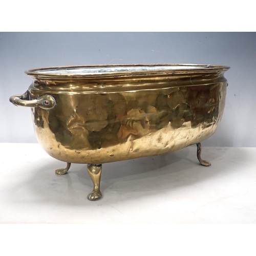 446 - A two handled brass Jardiniere, oval and with embossed coat of arms on four paw supports, 2ft W