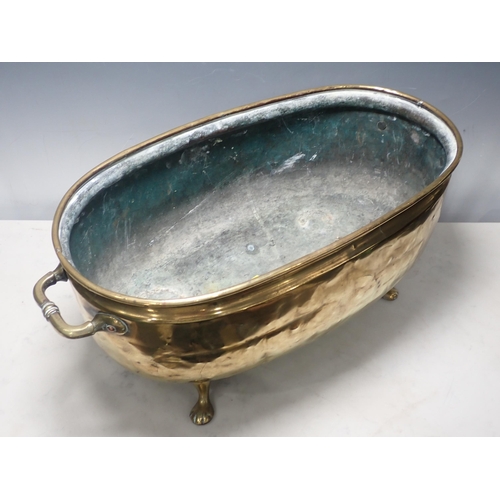 446 - A two handled brass Jardiniere, oval and with embossed coat of arms on four paw supports, 2ft W