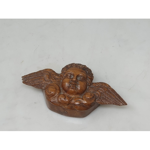 543 - A treen Snuff Box, the lid in the form of a winged Cherub, an olive wood Compact Mirror, a carved tr... 