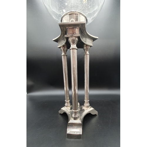 56 - A plated Candle Stand having triple column supports surmounted by clear glass bell shape shade, 2ft