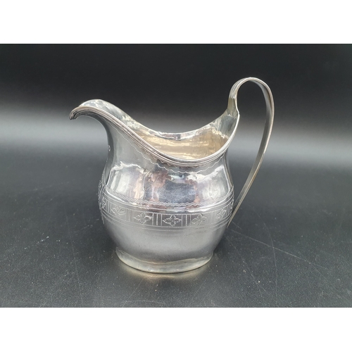 65 - A George III silver oval Jug engraved leakage friezes with shaped cartouche and reeded rims, London ... 