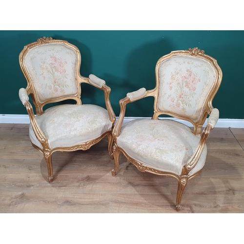 821 - A pair of French gilded open Elbow Chairs with cream floral needlework upholstery mounted upon cabri... 