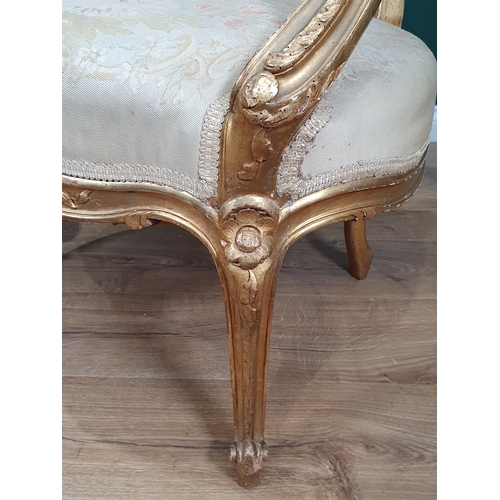 821 - A pair of French gilded open Elbow Chairs with cream floral needlework upholstery mounted upon cabri... 