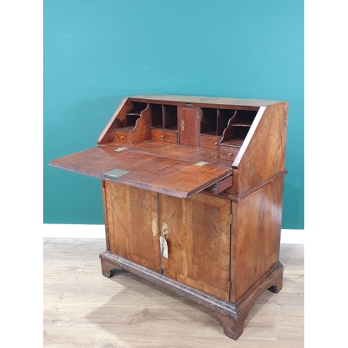 822 - An 18th Century figured walnut veneered Bureau with sloped fall front enclosing four drawers, a cent... 