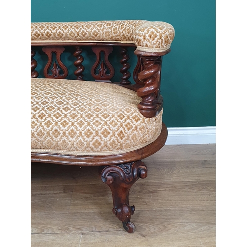 843 - A Victorian walnut Settee with upholstered rounded arms and back above spiral turned and pierced car... 