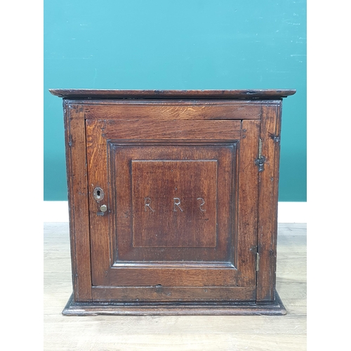 853 - An 18th Century oak Spice Cupboard fitted fielded panel door with carved initial R.R.S enclosing she... 