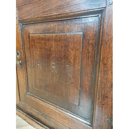 853 - An 18th Century oak Spice Cupboard fitted fielded panel door with carved initial R.R.S enclosing she... 